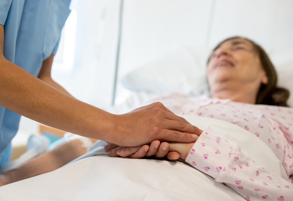 Closeup of a nursing holding hands with a patient as they trransition from palliative care to hospice care