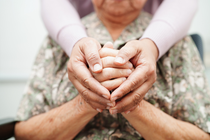 Elder woman pertaking in early palliative care services with hands enclosed